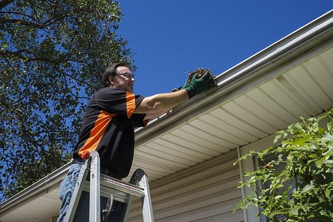 worker fixing a broken gutter on a house in Atherton